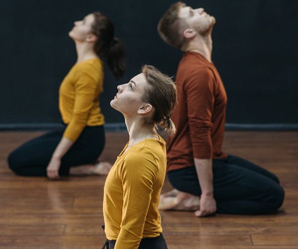 Group of people practicing synchronized movement in a dark stylish hall